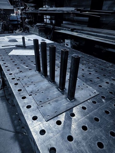 A row of short posts welded to base plates on the fixture table