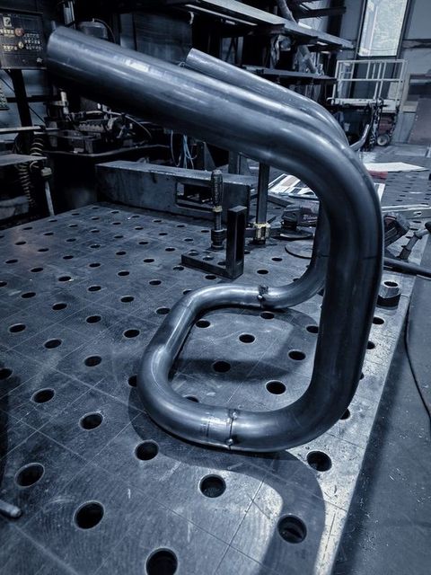 Two heavy bent tubes standing on the fixture table