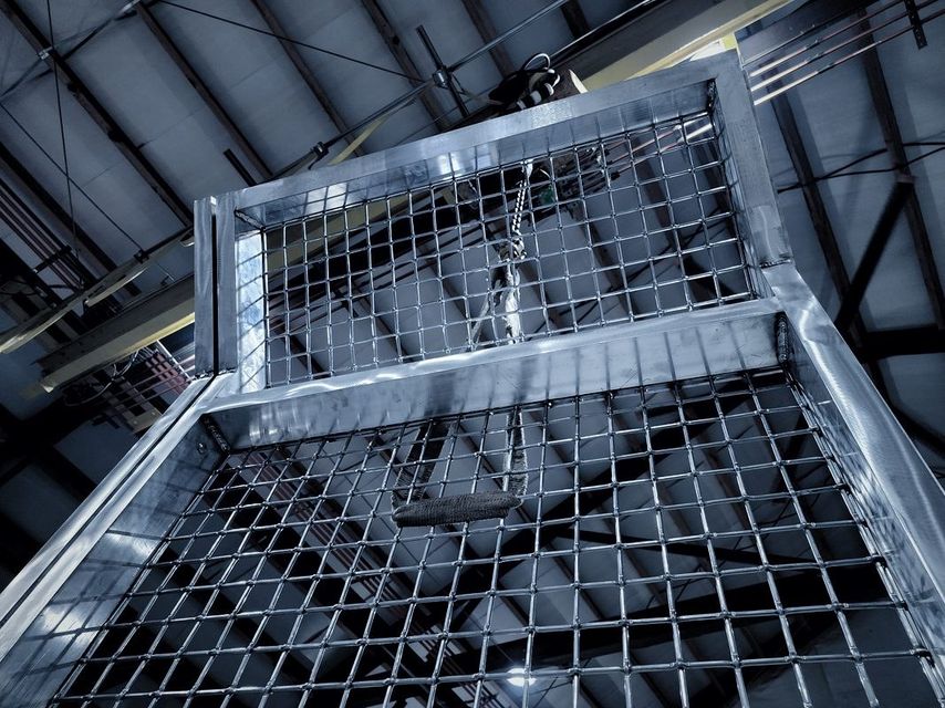 Looking up at wire mesh welded into a bright tube frame