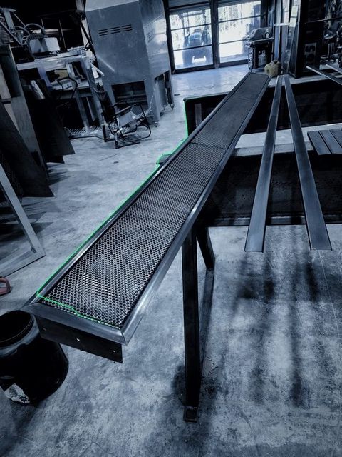 A long perforated metal tray on stands runs down the shop