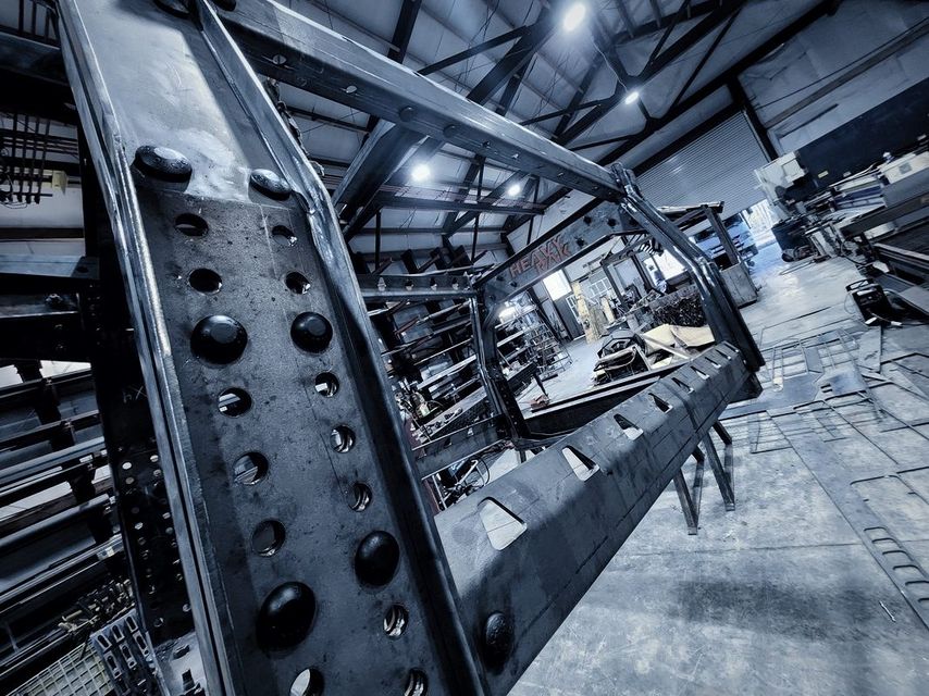 Close view of a heavy steel frame with rows of holes and dome head fasteners