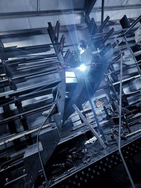A welding arc flares high up on the curved stair